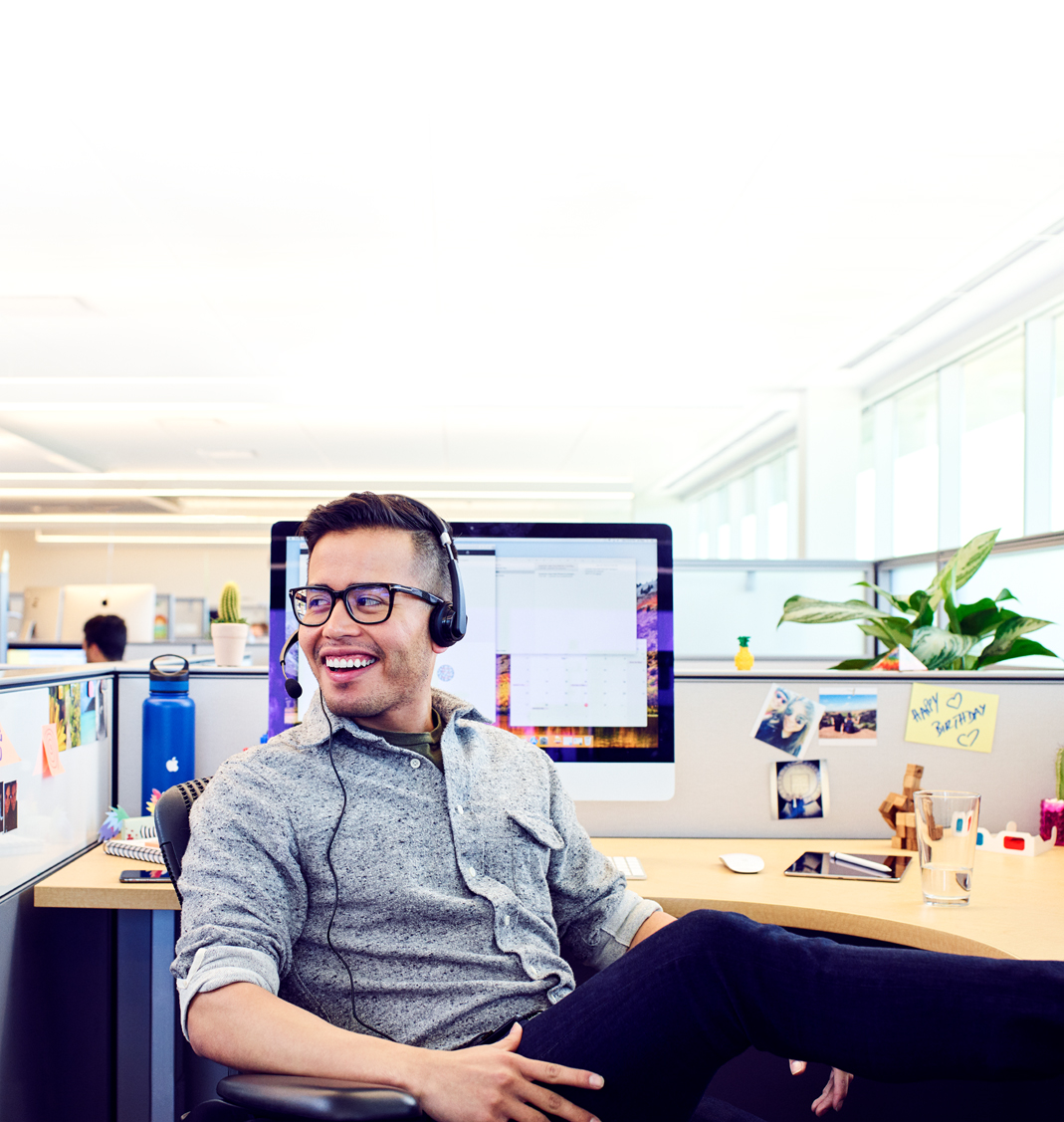 A male Apple Support Advisor relaxes between calls at his desk at the Apple campus.