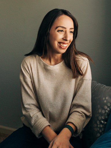 Photo portrait of Belqise, looking off to the side, laughing.