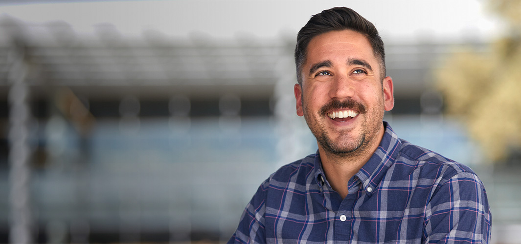 Marc regarde vers le côté en souriant à pleines dents.