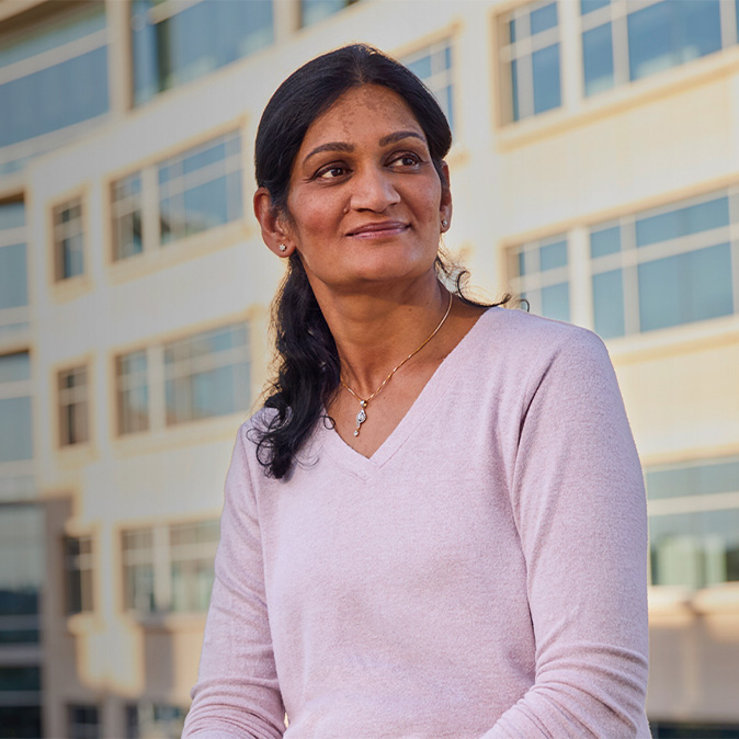 Ramani, assise devant un immeuble de bureaux, regarde vers le côté.