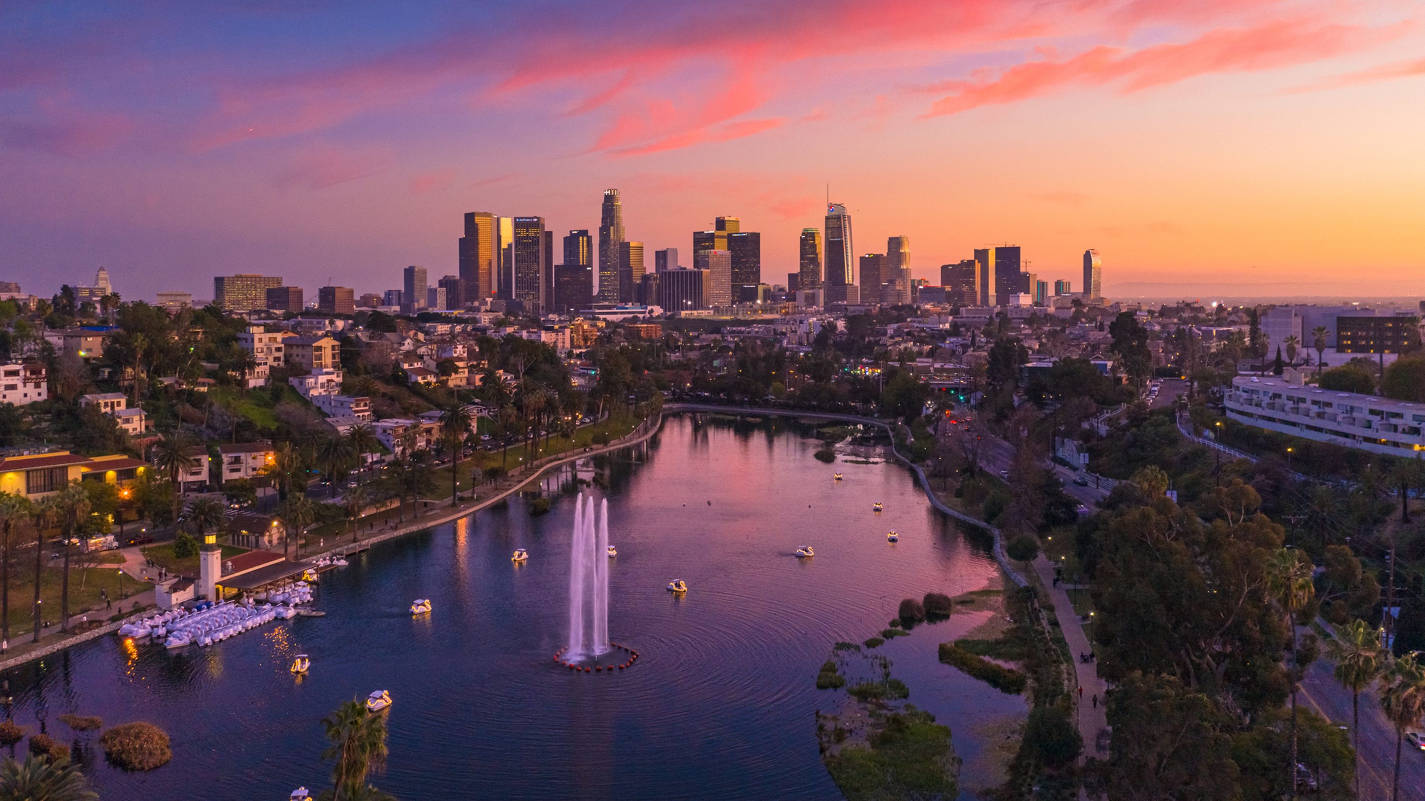 Vue aérienne des gratte-ciel de Los Angeles, avec un parc et un lac à l’avant-plan.