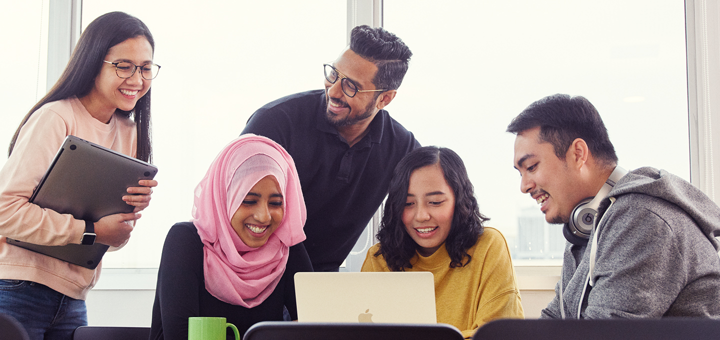 Des employés d’Apple, réunis pour discuter, regardent le MacBook de l’une d’entre eux.