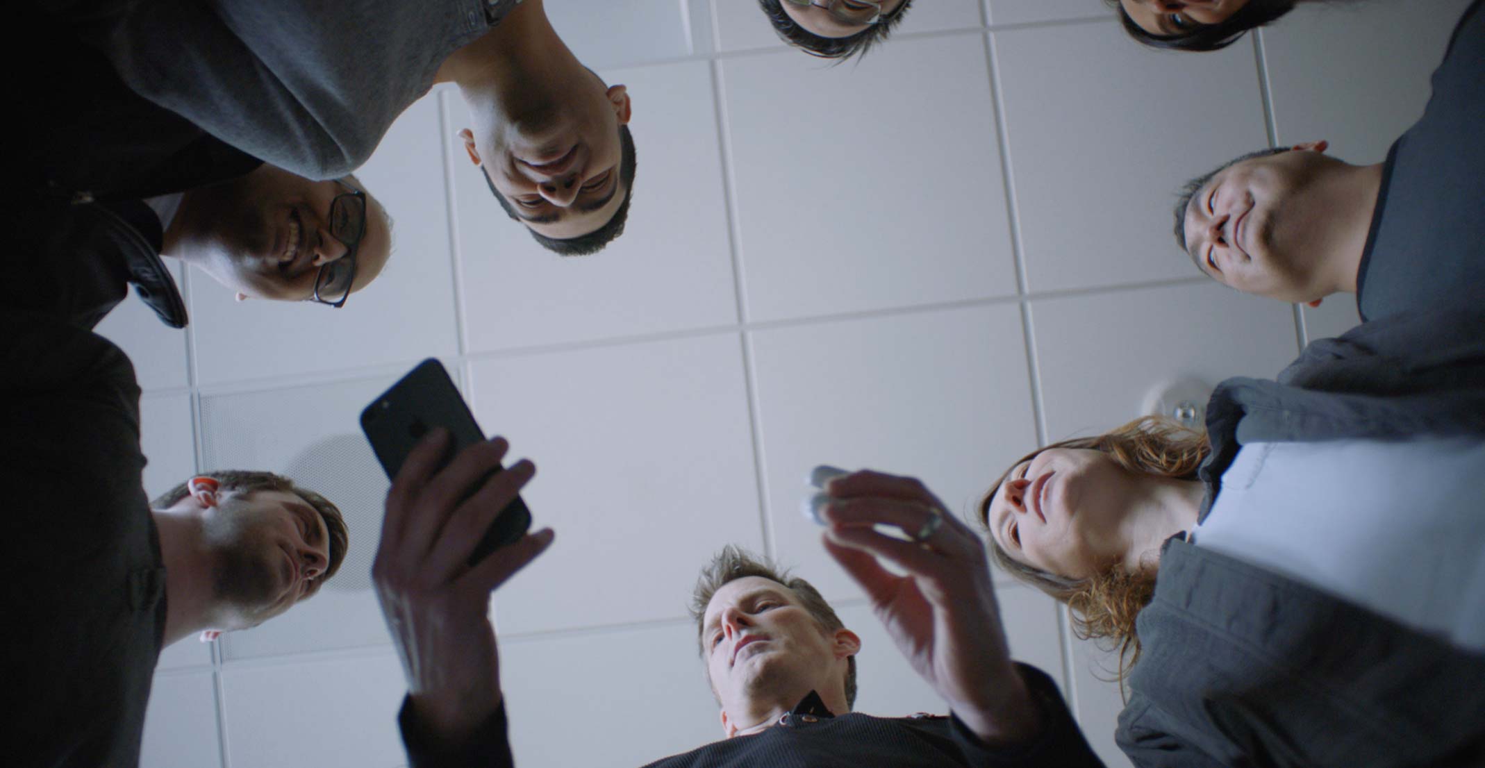 Jason, a manager in Apple’s Wireless Software Engineering group, holds an iPhone and a set of AirPods during a group meeting