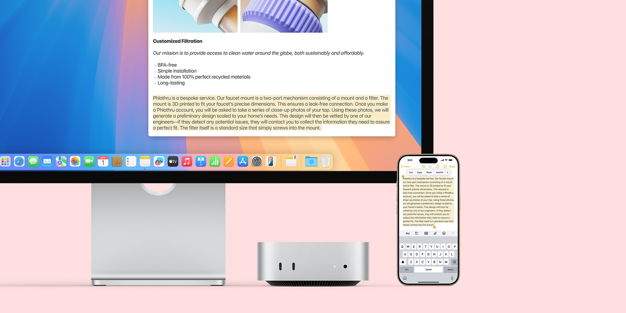 Mac monitor, silver Mac mini, and iPhone placed in a row, with the monitor display and the iPhone screen demonstrating the Universal Clipboard feature of copying and pasting from one Apple device to another