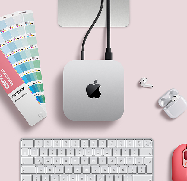 Vista desde arriba de un escritorio con una Mac mini color plata junto a unos AirPods, un Magic Keyboard color plata y blanco y una paleta de colores