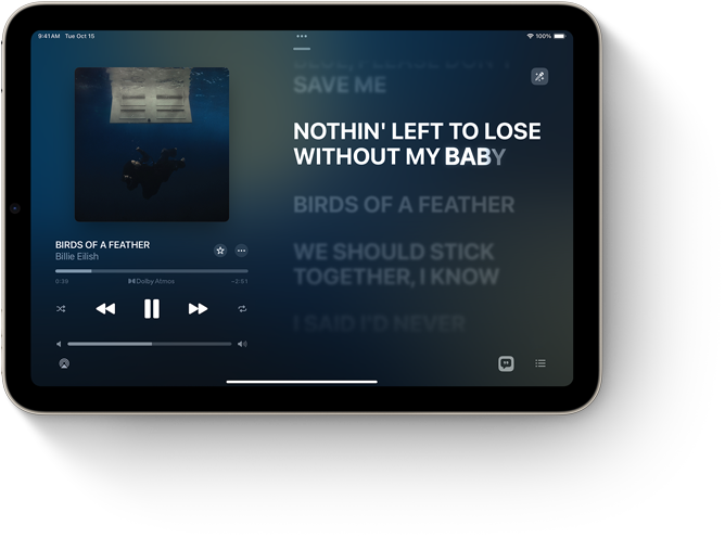 Horizontāli novietots iPad mini, demonstrējot Lyrics funkciju Apple Music aplikācijā.