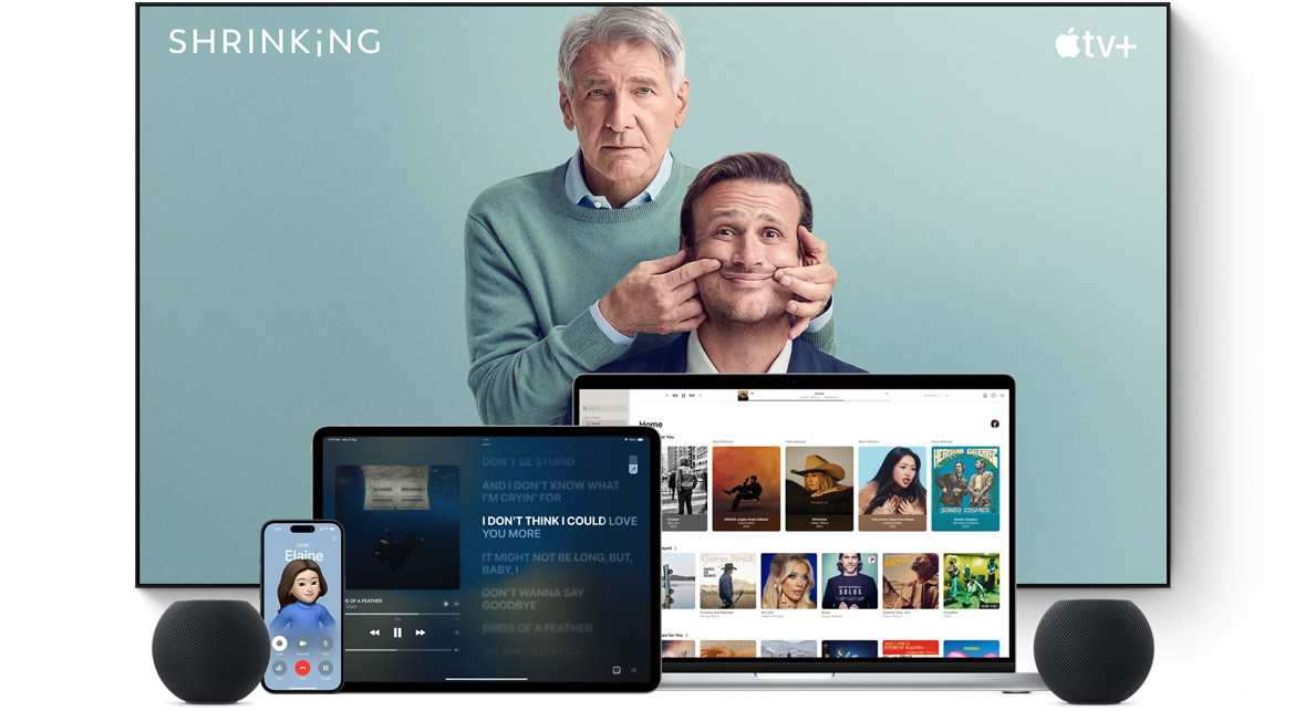 Large flat-screen television showing two male characters from the Apple TV+ series Shrinking. A MacBook Pro, an iPad, an iPhone and a Midnight HomePod mini are arranged in front.