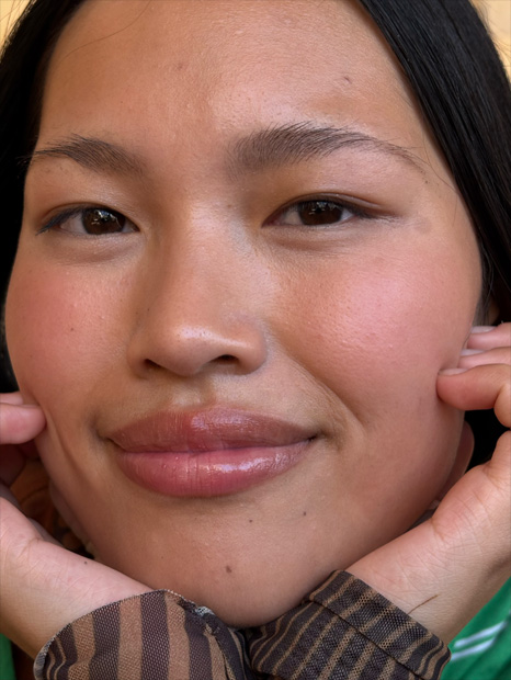 A zoomed-in portrait of a young woman demonstrating the 2x Telephoto capabilities of iPhone 16