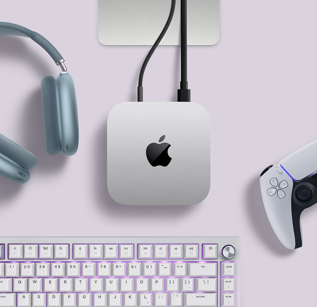 Prikaz srebrnog Maca mini odozgo s dva kabla priključena u stražnje priključke, a pored njega su plave slušalice AirPods Max, srebrna tipkovnica Magic Keyboard i bežični kontroler za igre