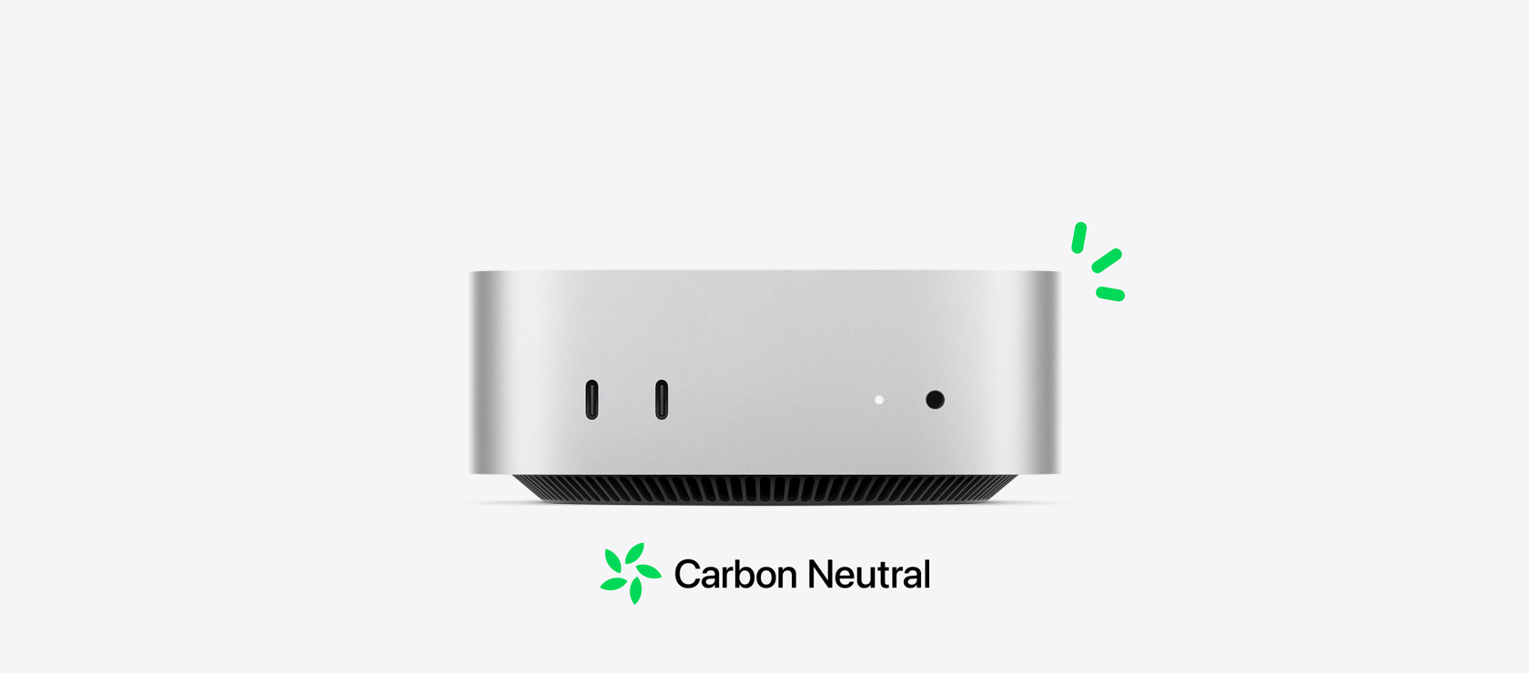 Front view of silver Mac mini showing front ports, with carbon neutral story illustrated by small green accents.