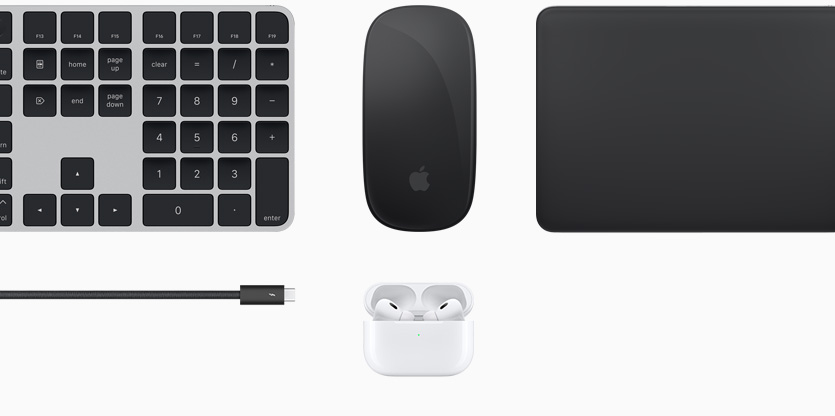 Various Mac accessories, including a black Magic Keyboard with Touch ID, a black Magic Mouse, a black Magic Trackpad, a black accessories cord, and white AirPods inside an open white charging case